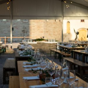 Långbord dukade med glas och grönt i festtältet på borggården, med slottsmuren i bakgrunden